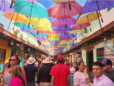 Calle decorada con coloridos paraguas en Guatapé, un punto turístico emblemático para fotografía y recorridos culturales en Antioquia.